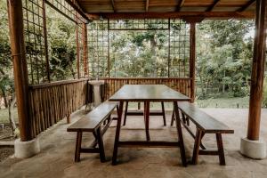 une table en bois et des bancs sur une terrasse couverte dans l'établissement The Boom Cottage, à Aposentillo