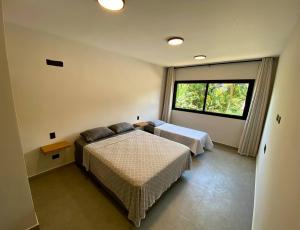 ein Schlafzimmer mit zwei Betten und einem Fenster in der Unterkunft Villa Julião in Ilhabela + 15 Fotos