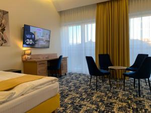 a hotel room with a bed and a desk and chairs at Piramida in Bolesławiec