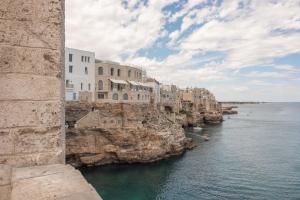 un grupo de edificios en un acantilado junto al agua en MandorleOlio Versomare, en Polignano a Mare