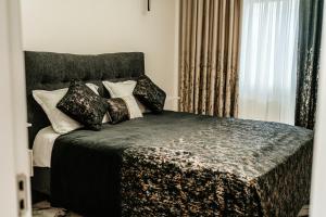 a bedroom with a bed with black and white pillows at Jessica luxury Apartament in Curtea de Argeş