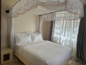 a bedroom with a white bed and a window at Lakeview Apartments - The Nest in Mbita