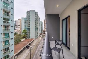a chair sitting on the balcony of a building at Sua estadia exclusiva a poucos passos do Mar em Meia Praia - FFS in Perequê