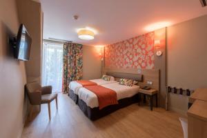 Habitación de hotel con cama y silla en Logis Grand Hôtel Des Bains en Salins-les-Bains