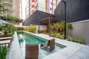 a swimming pool with two chairs next to a building at My Place in Curitiba
