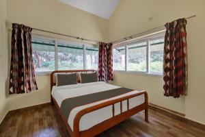 Un dormitorio con una cama y dos ventanas en KODAI MIST Forest Resort, en Kodaikanal