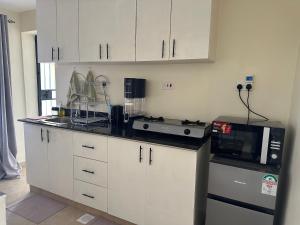 a kitchen with white cabinets and a microwave at Lakeview Apartments - The Nest in Mbita +19 photos