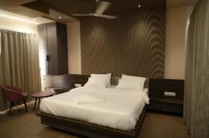 a bedroom with a large bed with white sheets at Kusum Resort in Badami