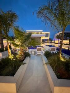 RrushkullInfinity Villa的一条设有椅子、棕榈树的走道和一栋建筑物