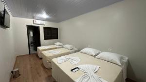 drie bedden in een kamer met witte muren bij Cores De Outono Suítes in Canela