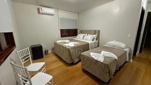 een hotelkamer met 2 bedden en 2 stoelen bij Cores De Outono Suítes in Canela