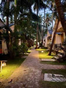 a resort street with palm trees and a pathway at Sameer beachfront Cottages in Canacona