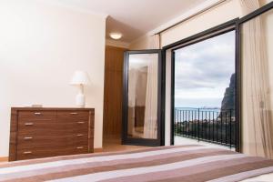 a bedroom with a large window with a view of the ocean at Elegantes Haus In Santana Mit Garten Und Grill in Faial +26 photos