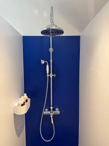 La salle de bains est pourvue d'un mur bleu et d'une douche. dans l'établissement Le Grenier d'Antan - Near Mont-Saint-Michel, à Pontorson