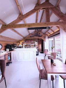 ein Raum mit Holztischen und -stühlen und einer Küche in der Unterkunft Wellness Sauna Beauty Farm Midwolda in Midwolda
