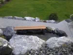 a bench sitting on top of rocks in a pond at Wohnung Mit Großer Gartenterrasse Und Ausblick in Argenbühl