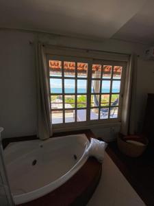 eine große Badewanne im Bad mit Fenster in der Unterkunft Pousada Chic N Choc in Morro de São Paulo