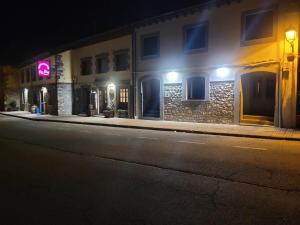 une rue déserte la nuit avec un bâtiment portant une enseigne rose dans l'établissement La Era Rooms, à Lario
