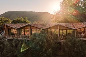 a house with a wrap around deck with the sun shining at Alpeta Agrotourism & Winery - Roshnik , Berat in Berat