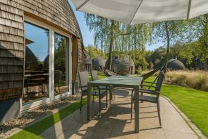 ein Tisch und Stühle auf einer Terrasse mit einem Sonnenschirm in der Unterkunft Nordkugel - Rundes Wohnglück am Tollensesee in Wustrow