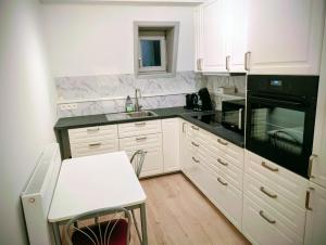 a kitchen with white cabinets and black appliances at Duplex 3BR apartment near supermarkets & metro in Brussels