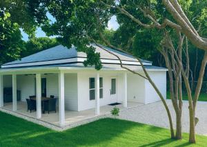 a white house with a table in a yard at La Maison Blanche- Close Beach Access in Gregory Town