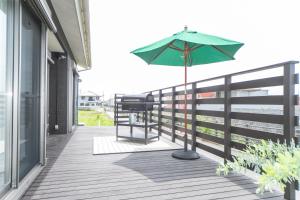 a green umbrella on a balcony with the ocean at Awaji Riverside Terrace in Shizuki - Vacation STAY 81986v in Shizuki