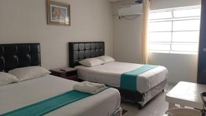 une chambre d'hôtel avec deux lits et une fenêtre dans l'établissement Hostal Independencia, à Santa Cruz de la Sierra