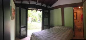 ein Schlafzimmer mit einem Bett und einer offenen Tür in der Unterkunft Casa da Jataí - Piscina e Pomar - Barra do Sahy in São Sebastião + 59 Fotos