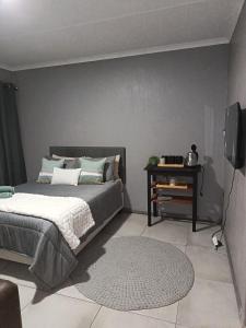een slaapkamer met een bed en een televisie en een tapijt bij J & M Elegant escape 2 in Centurion