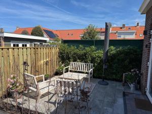 a patio with two chairs and a table and a fence at Casa Del Faro in Westkapelle
