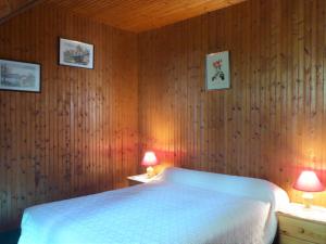 Schlafzimmer mit einem weißen Bett und Holzwänden in der Unterkunft Le Buisson in Montlouis-sur-Loire