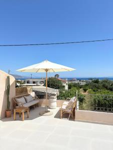 a patio with an umbrella and chairs on a roof at Athina's Cozy Guest House in Kamisianá