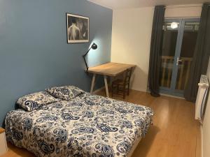 ein Schlafzimmer mit einem Bett und einem Tisch mit einer Lampe in der Unterkunft 70m2 dans une ferme en Isère in Le Pont-de-Beauvoisin