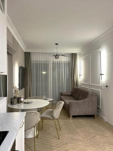 un salon avec un canapé, une table et des chaises dans l'établissement Let's Sea SPA - Premium Apartamenty z ogródkiem, przyjazne zwierzętom, à Gąski 28 autres photos