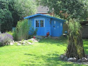 ein blaues Außenhaus in einem Garten in der Unterkunft Wohnung in Gießelrade mit Großem Garten - b48578 in Ahrensbök