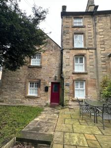 モファットにあるThe Oldest House Located in the heart of Matlockの赤い扉とテーブルのあるレンガ造りの家