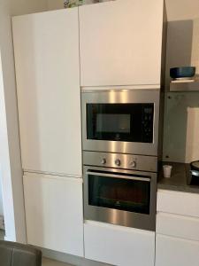 une cuisine avec deux fours et des placards blancs dans l'établissement A casa di ANDREA - 25 MINUTI DAL DUOMO, à Sesto San Giovanni