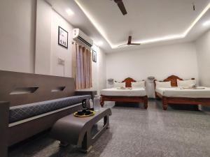 a room with three beds and a table in it at The Hotel Eden Beach in Puducherry