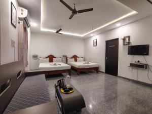 a room with two beds and a flat screen tv at The Hotel Eden Beach in Puducherry