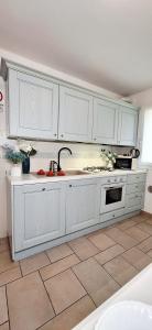 une cuisine avec des armoires blanches et un sol carrelé dans l'établissement Appartamento Perla Marina, à Sottomarina