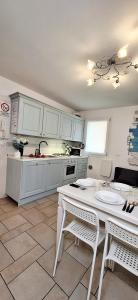 une cuisine avec des placards blancs et une table et des chaises blanches dans l'établissement Appartamento Perla Marina, à Sottomarina
