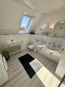 ein Badezimmer mit zwei Waschbecken und einer Toilette und einem Spiegel in der Unterkunft Ferienhaus Blinkfuer in Neuharlingersiel + 23 Fotos