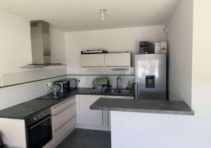 eine Küche mit weißen Schränken und einem Kühlschrank in der Unterkunft Appartement Cosy in Le Crès