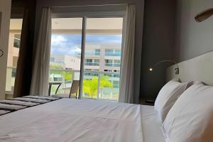 a bedroom with a white bed and a large window at Brisas do Lago - Apartamentos in Brasilia +157 photos