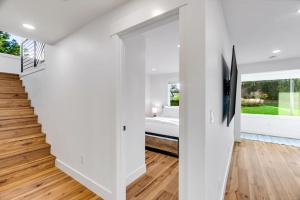 einen Flur mit weißen Wänden, Holzböden und einer Treppe in der Unterkunft Sunny 3BR Retreat Near Everett Waterfront in Everett