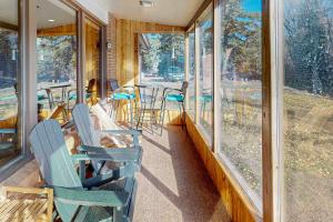 a porch with rocking chairs and tables and windows at Rainbow Riverhouse in South Fork