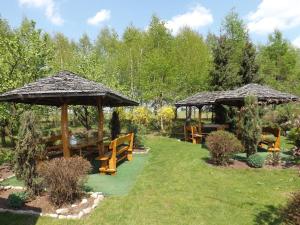 two picnic tables and umbrellas in a garden at Oberża in Czeladź