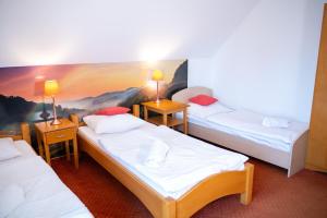 three beds in a room with a painting on the wall at Oberża in Czeladź
