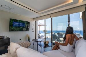 une femme assise sur un canapé dans un salon dans l'établissement Fotinari X-View Villa, Plakias ,Costline villaotinar, à Plakias